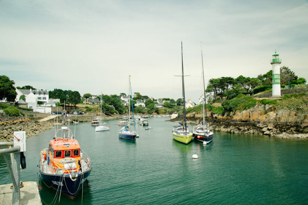 Bateaux à voile et vedettes dans le chenal du port de Doëlan entre les deux phares