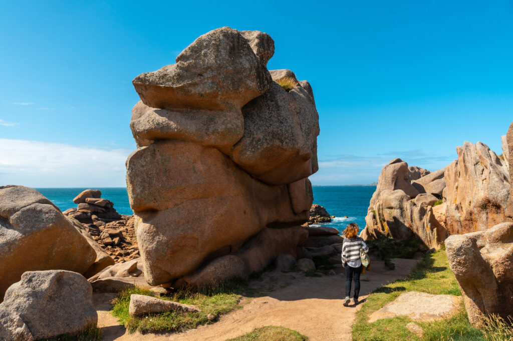 Randonneuse devant un rocher de granit rose sur le sentier des douaniers à Ploumanac’h