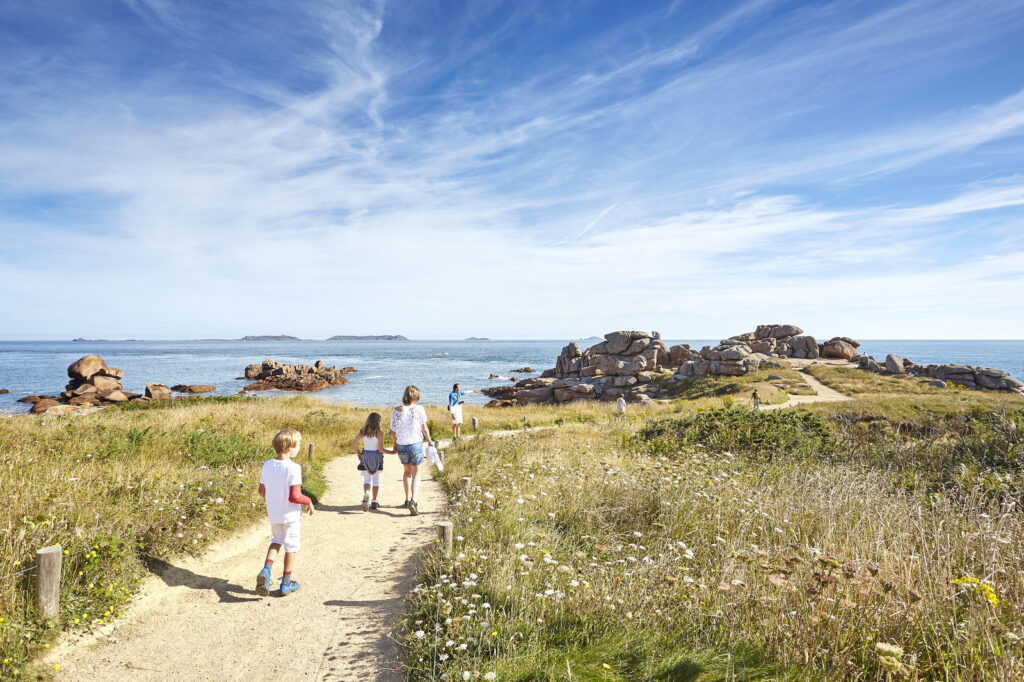 Famille en randonnée sur le sentier des douaniers en direction de la mer à Ploumanac’h