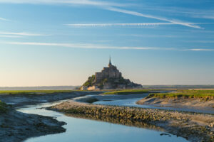 Vue panoramique du Mont-Saint-Michel entouré de la baie et des canaux à marée basse au lever du jour