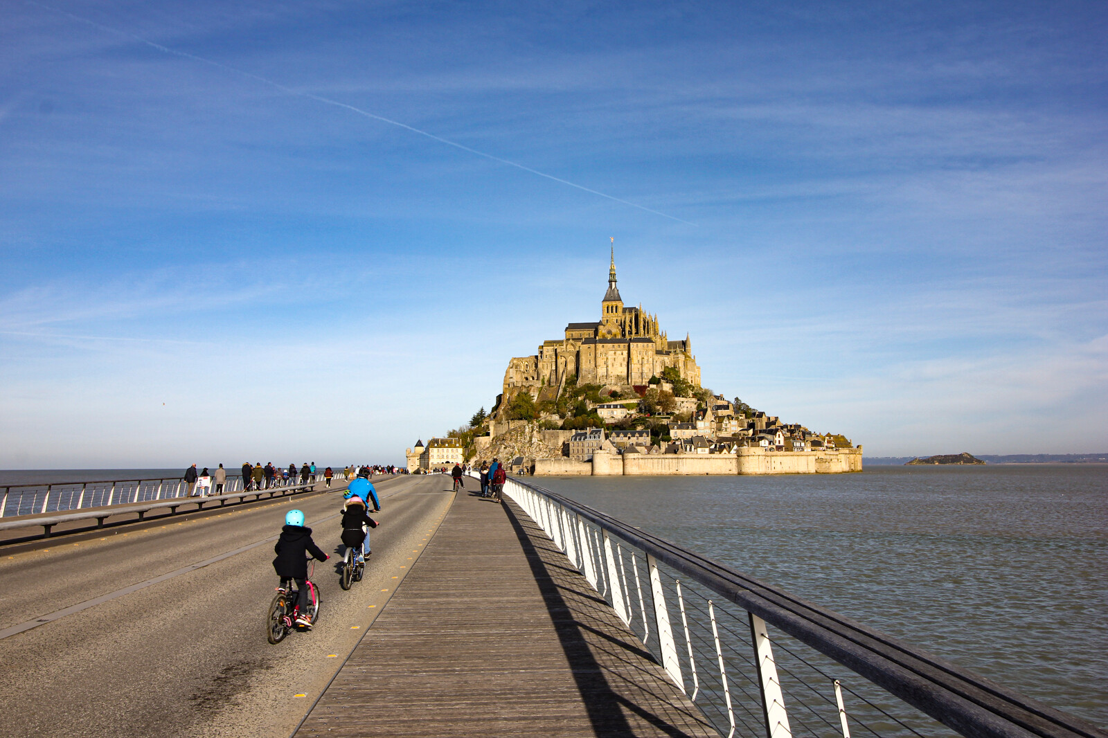 Cyclistes empruntant la passerelle du Mont-Saint-Michel en direction de l’abbaye