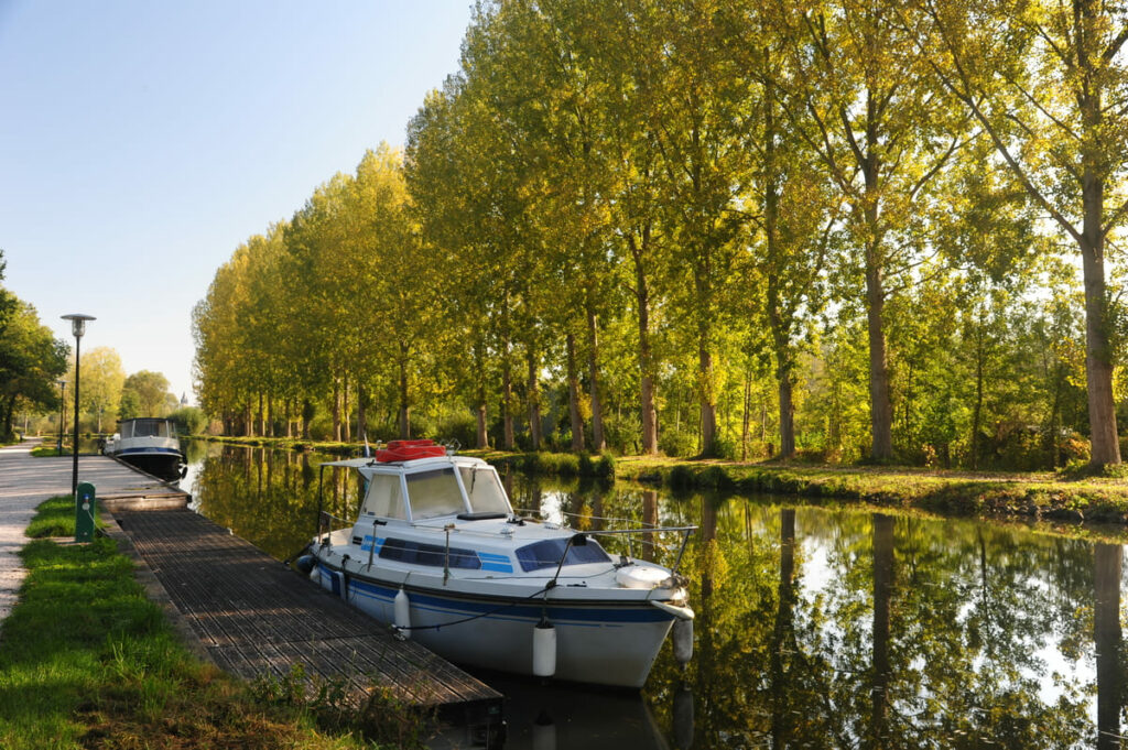 Bateaux amarrés sur le canal bordé d’arbres dorés dans la vallée de la Somme