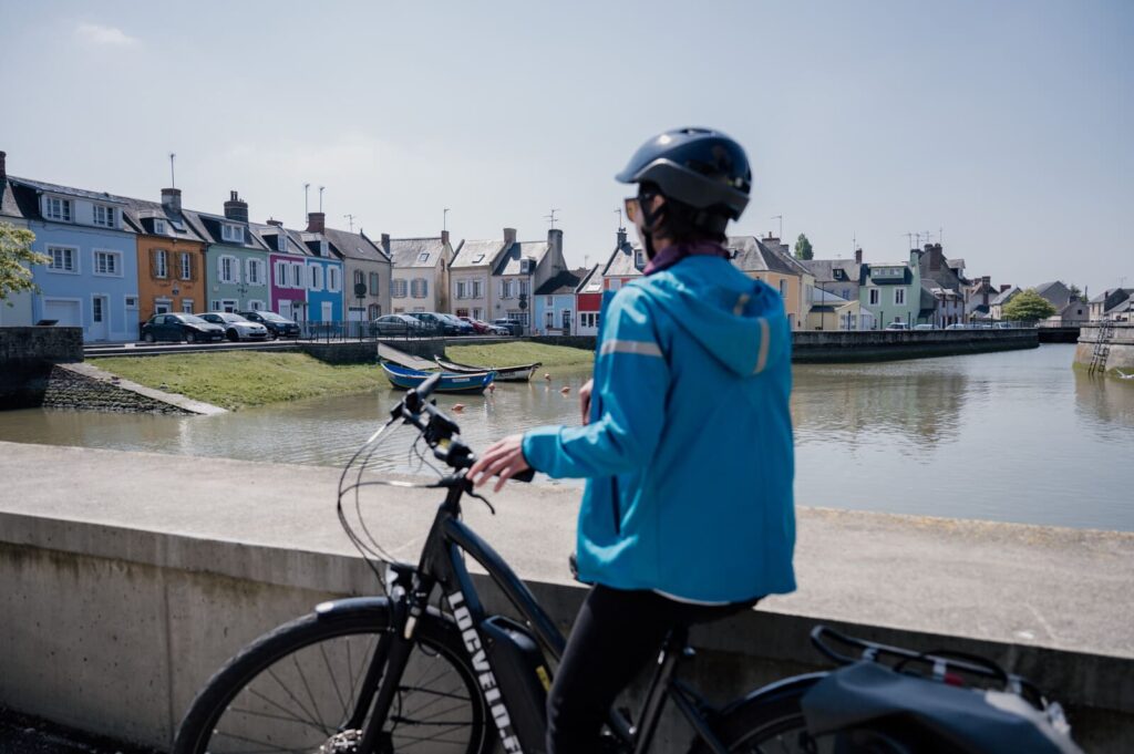 Cycliste observant les maisons colorées d'Isigny-sur-Mer
