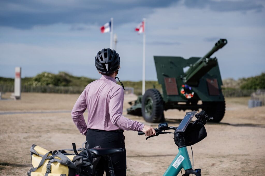 Cycliste devant un canon commémoratif sur les plages du Débarquement