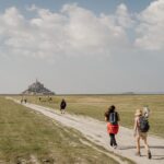 Randonneurs en marche vers le Mont Saint-Michel à travers les herbus