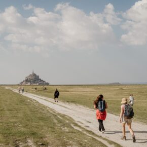 Randonneurs en marche vers le Mont Saint-Michel à travers les herbus