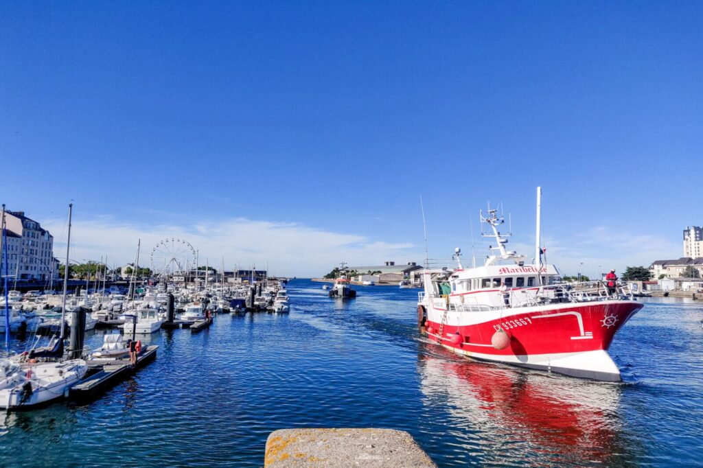 Bateau de pêche entrant dans le port de Cherbourg avec ses quais animés