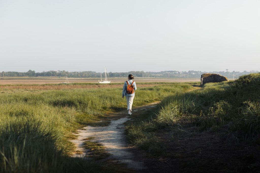 Randonneur sur un sentier du Havre de Regnéville au cœur des marais et herbus