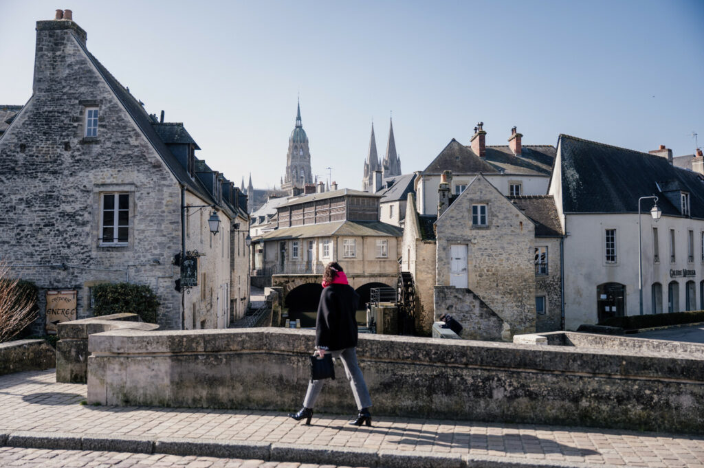 Femme marchant dans les rues anciennes de Bayeux avec la cathédrale en arrière-plan