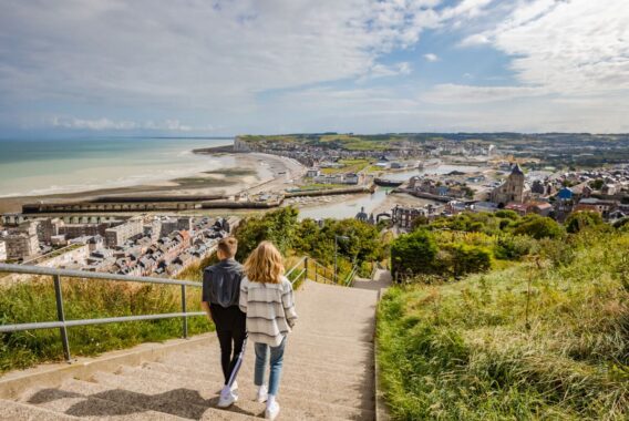 Deux promeneurs descendant les escaliers avec vue sur Le Tréport et la mer
