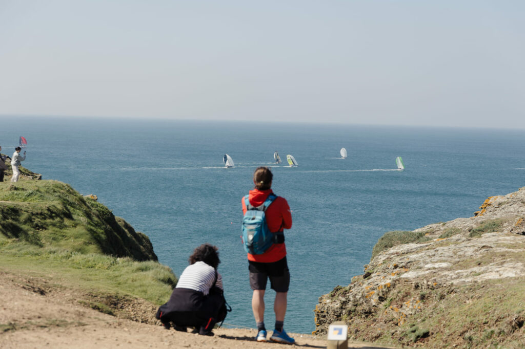 Randonneurs observant des voiliers depuis les falaises de l’île de Groix, Bretagne sud