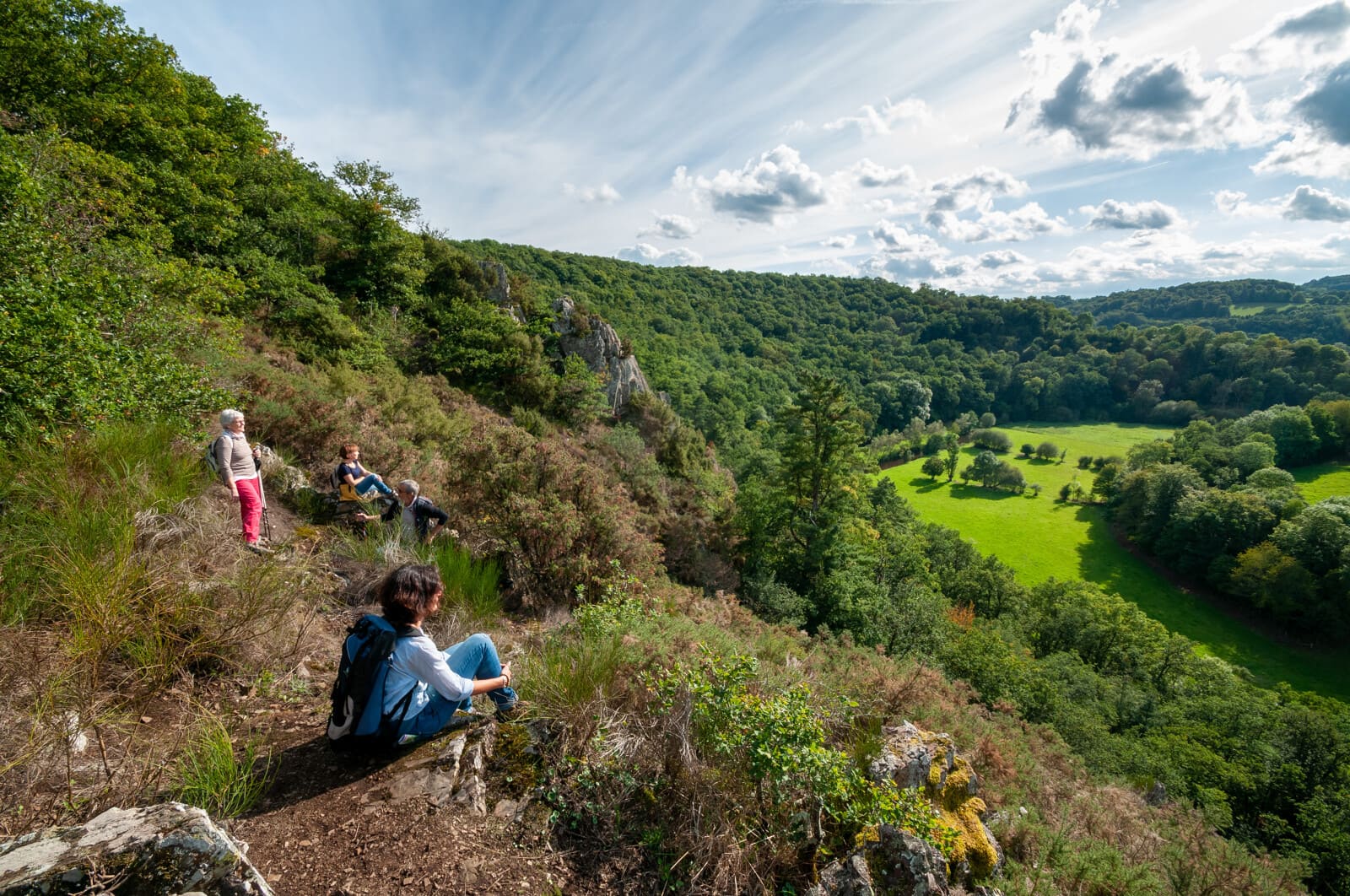 Famille de randonneurs en pause sur les hauteurs d’un sentier escarpé en Suisse Normande.