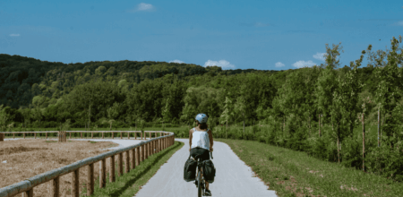 Cycliste roulant sur la voie verte aménagée à Courcelles-sur-Seine sous un ciel bleu.