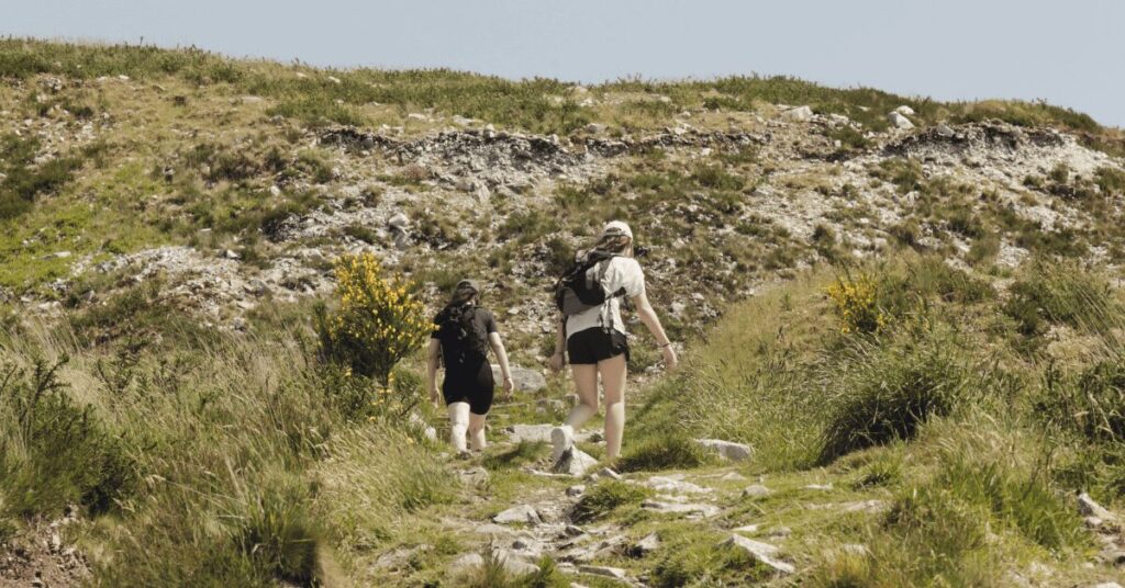 Deux randonneuses équipées montant un sentier rocheux exposé au soleil par forte chaleur