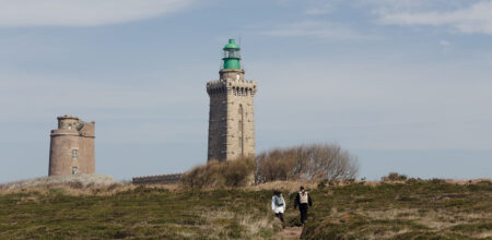 Deux randonneurs seuls sur la lande du Cap Fréhel face au phare en arrière-saison